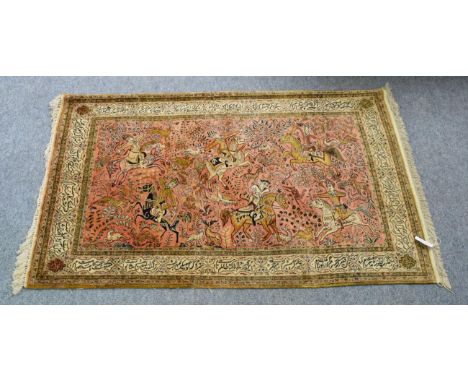 Ghom style silk rug, the salmon pink field depicting a hunting scene, enclosed by cartouche borders of Islamic verse, 165cm b