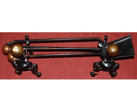 A pair of Victorian black painted wrought iron and brass fire dogs; together with three matching fire tools (5)