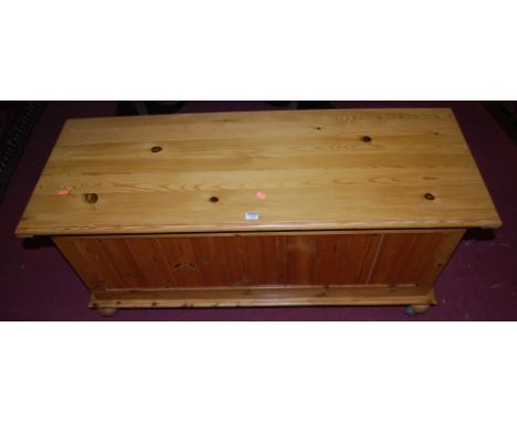 A modern stained pine hinged top blanket box, raised on roller castors, w.126cm