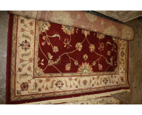 A VINTAGE FLOOR RUG WITH RED AND GOLD COLOURED DESIGN TOGETHER WITH A BRASS FIRE FENDER