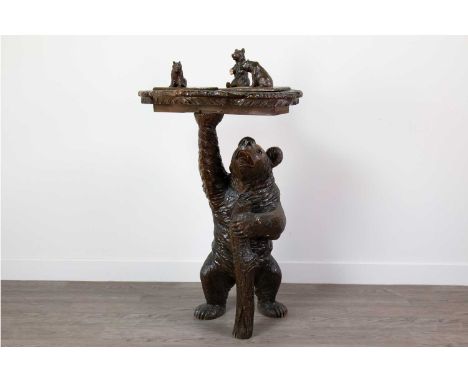 GOOD BLACK FOREST SMOKING TABLE,late 19th century, in lindenwood, the base modelled as a bear clutching a tree-trunk, the hin