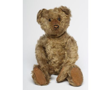 An early German straw filled teddy, possibly Steiff, with button eyes, sewn nose, felt pads, swivel joints, hump and internal