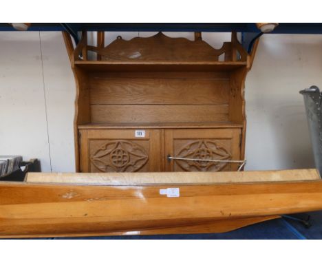 An oak carved wall hanging shelf with cupboard and a model wooden boat