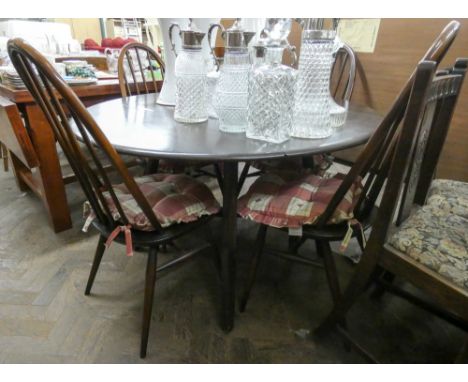 An Ercol oval oak drop leaf dining table and four Windsor style stick back chairs 