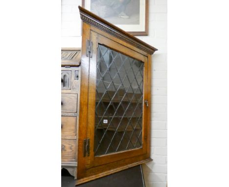 An oak wall hanging corner cabinet with glazed lead light door 