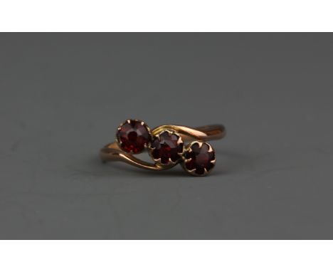 A 9ct yellow gold garnet set crossover ring, (J).