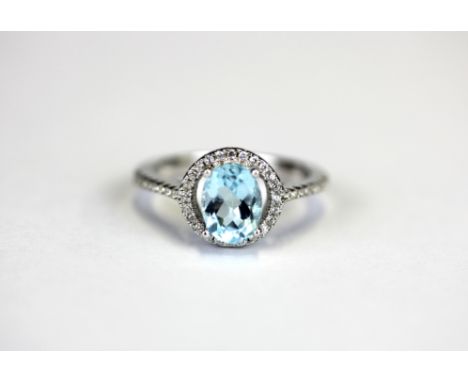 A 925 silver halo ring set with an oval cut blue topaz and white stones, (L).