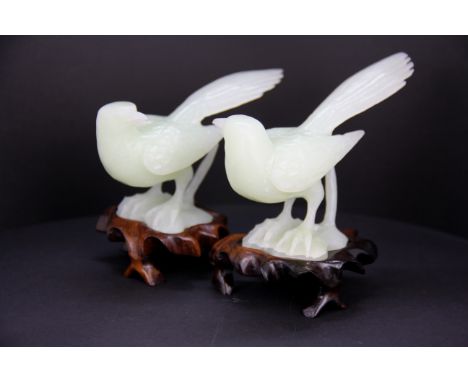 A pair of Chinese carved jade / hardstone figures of birds on carved wooden bases, L. 13cm. H. 11cm.