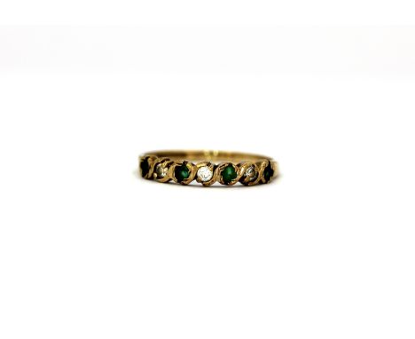 A 9ct yellow gold emerald and white stone set half eternity ring, (M.5).