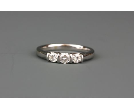 A white metal (tested 18ct white gold) ring set with three brilliant cut diamonds, (K).