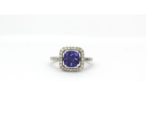 An 18ct white gold cluster ring set with a cushion cut tanzanite surrounded by brilliant cut diamonds, (O).