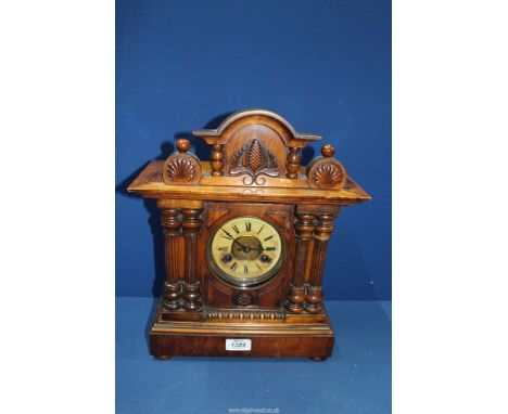 A Mantle clock with pine cone detail to the pediment and columns to either side of the clock face, with key and pendulum, 12"
