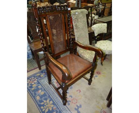 An Oak framed hall Armchair of uncommon design with cranked arm rests, caned back panel, turned legs and back supports and ha