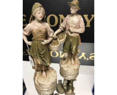 PAIR OF ROYAL DUX MALE AND FEMALE FIGURE ORNAMENTS carrying baskets of fish, decorated in pastel tones with gilt highlights, 