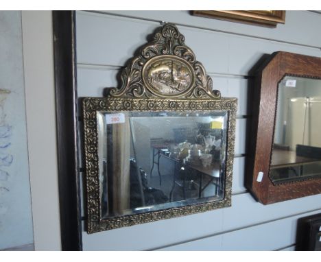 A vintage brass pressed mirror with bevel edge and village imagery