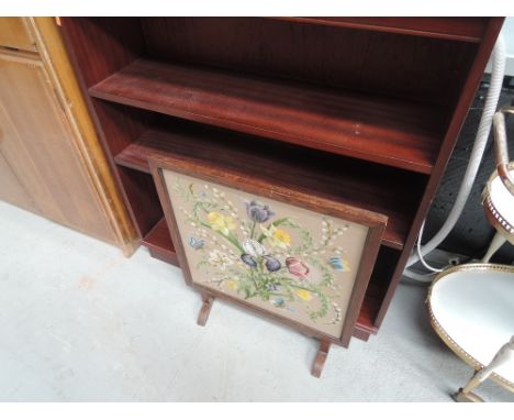 A modern mahogany effect bookcase and an oak framed embroidered firescreen