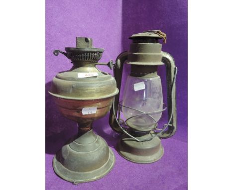 A vintage oil burning lamp and similar storm lantern