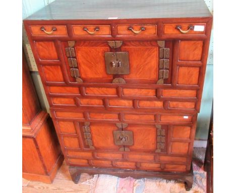 A modern Ming-style hardwood cabinet with an arrangement of drawers around a cupboard, enclosed by a pair of doors on bracket