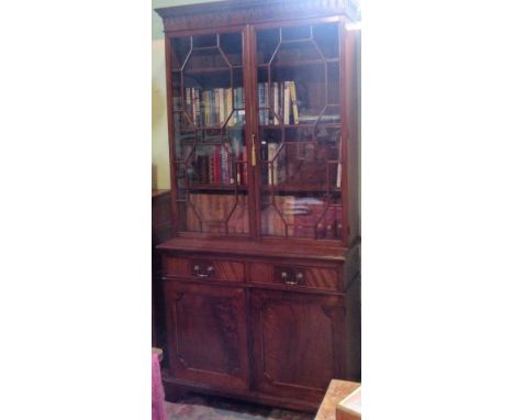 A George III-style mahogany bookcase cabinet, having dentil cornice over a pair of astragal glazed doors, enclosing three adj