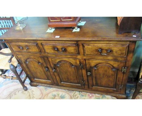 A reproduction oak low dresser, the rectangular top with moulded edge over three frieze drawers and three fielded panel cupbo