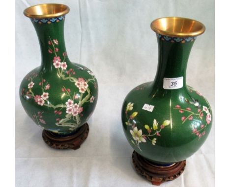 A pair of 20th century jade green ground Oriental cloisonne vase on carved wooden stands.