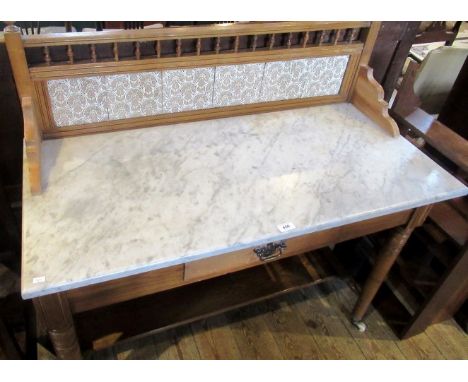 An Edwardian pine washstand, having a tile back and marble top over frieze drawer on ring turned tapering supports and cerami