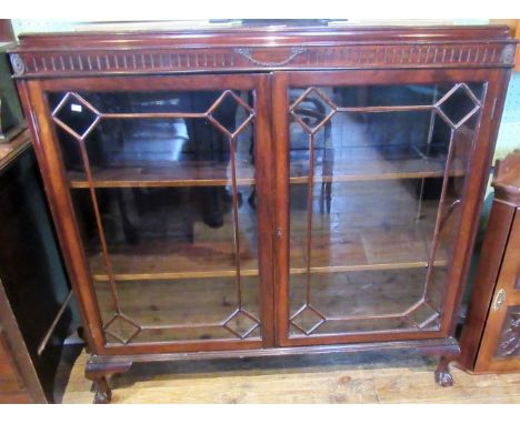 An Edwardian mahogany bookcase, having a a caddy top over fluted and swag moulded frieze, above a pair of glazed doors, enclo