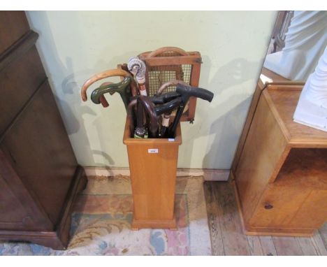 A 20th century light oak stick stand with brass cup side handles, containing a quantity of polished hardwood, two tennis racq