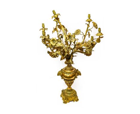 A Gilt Metal Nine-Light Candelabrum, in Louis XV style, as flowers issuing from a baluster vase cast with ram's mask handles 