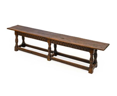 An Oak Double Joint Stool, the one-piece top with chip carved edge above a nulled frieze, on six baluster turned and nulled s