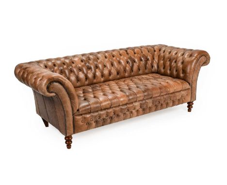 A Victorian-Style Chesterfield Sofa, modern, covered in close-nailed buttoned light-brown leather, the rounded arm supports a