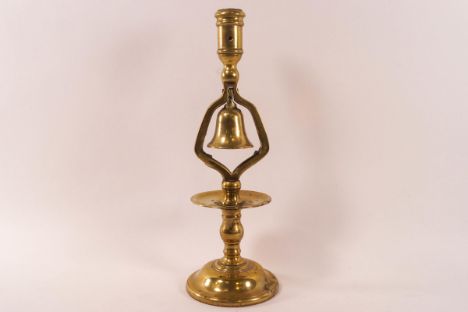A brass candlestick with a bell above the drip pan on flared domed foot, 31.5cm high