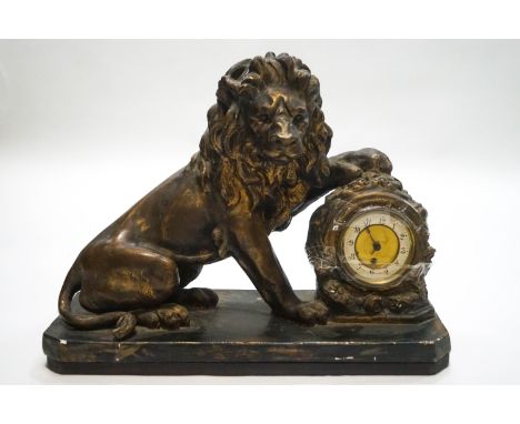 A French plaster mantel clock, modelled as a lion with its paw upon the clock, 46cm high x 59cm wide