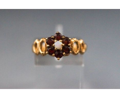 A yellow metal cluster ring set with a opal and surrounded by garnets. Hallmarked 9ct gold, london, 1979. Size O 3.2 grams