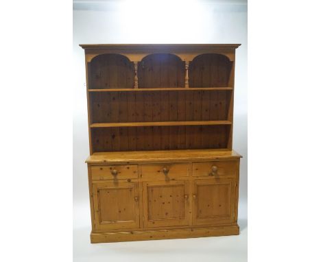 A 20th century pine dresser, the two shelf rack over three drawers and cupboards, 198cm high x 156cm wide x 41cm deep