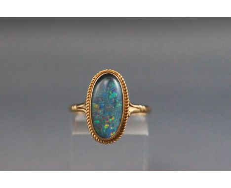 A yellow metal ring set with an oval cabchon opal triplet. Size P 2.7 grams