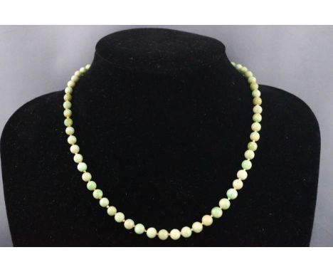 An early 20th century jade bead necklace, the beads graduated approx. 6.5mm - 4.5mm, knotted on a bolt ring clasp, stamped ‘9
