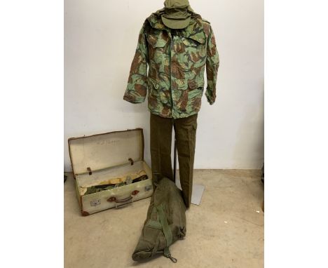 An early 1960s suitcase with assorted military items. A combat jacket, 1950s trousers, a kit bag, hat and other accessories 