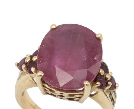 Ruby and diamond 18ct gold dress ring, the large oval cut stone measuring approximately 15mm by 12mm by 6.5mm deep, with a tr