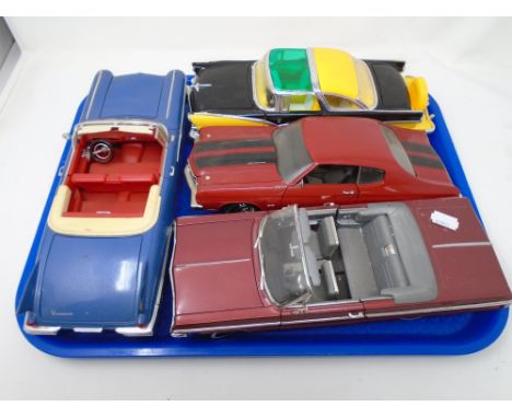 A tray containing four large scale die cast vehicles.