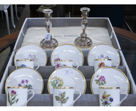 A boxed set of six Royal Worcester floral-printed coffee cups and saucers to/w a pair of loaded silver baluster candlesticks,