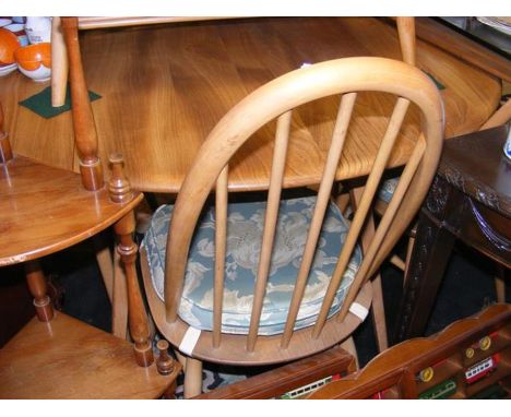 A circular Ercol table with four matching chairs plus one other similar chair