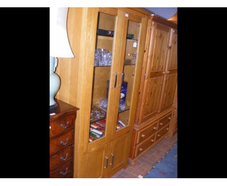 A modern light oak display cabinet with glazed upper section and cupboards below 