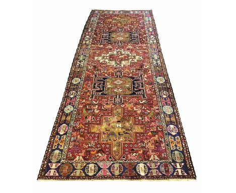 SOUMAK KELLEH RUG, 325cm x 116cm, rows of medallions on a ruby field of stylised figures and motifs within corresponding bord