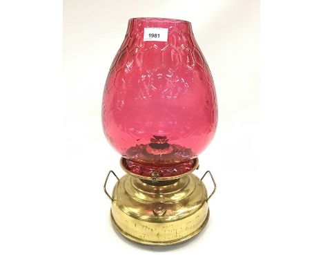 Early 20th century brass oil lamp, of squat form with bulbous, honeycomb moulded cranberry glass shade, 41cm high