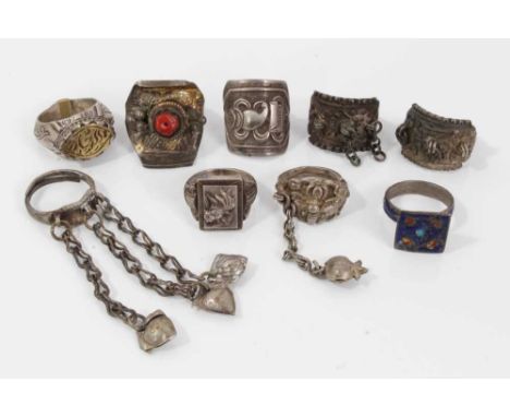 Nine Eastern silver and white metal rings including a seal ring, one set with coral, enamelled ring, Chinese ring with fish d
