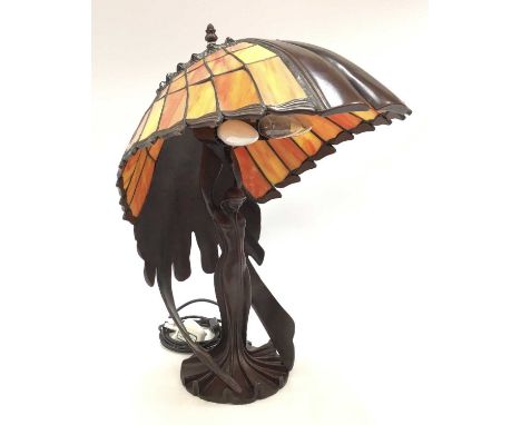 Tiffany style stained glass lamp, with Art Deco style figure holding aloft coloured glass shade. 54cm high