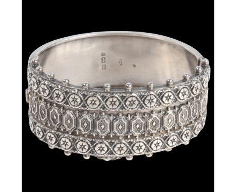 A late Victorian silver Etruscan Revival hinged bangle, indistinct maker, Birmingham 1883, band width 29.7mm, internal circum