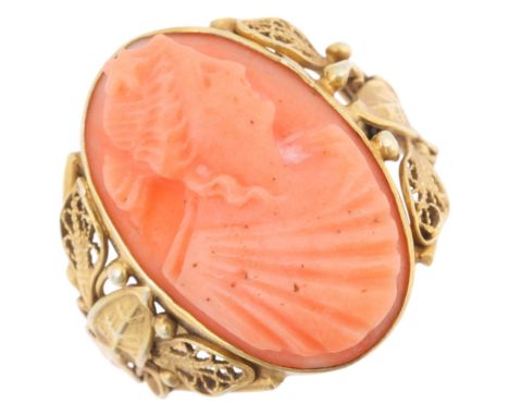 An Art Nouveau French 14ct coral cameo ring, relief carved depicting Nyx (Goddess of the Night), within pierced wirework leaf