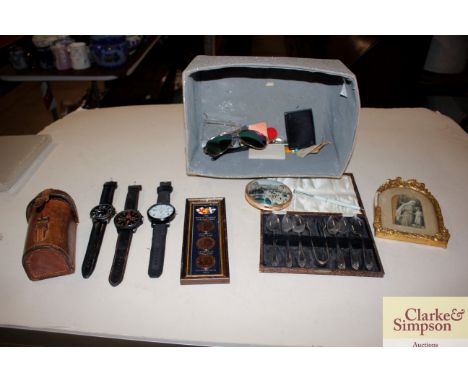 A box of miscellaneous items to include cased teaspoons and sugar nips, a vintage leather container, etc. 